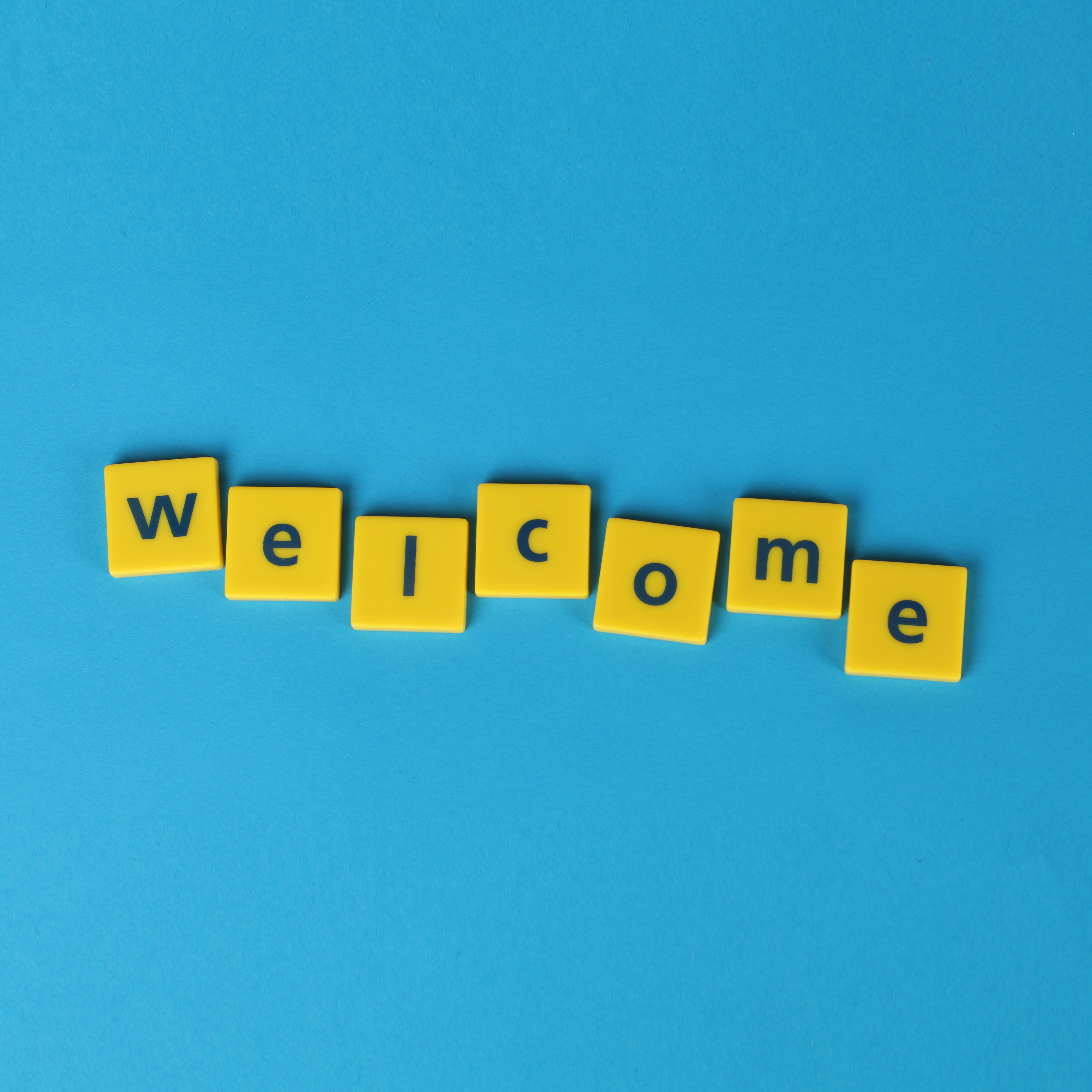 Yellow tiles on blue background that spell “welcome”