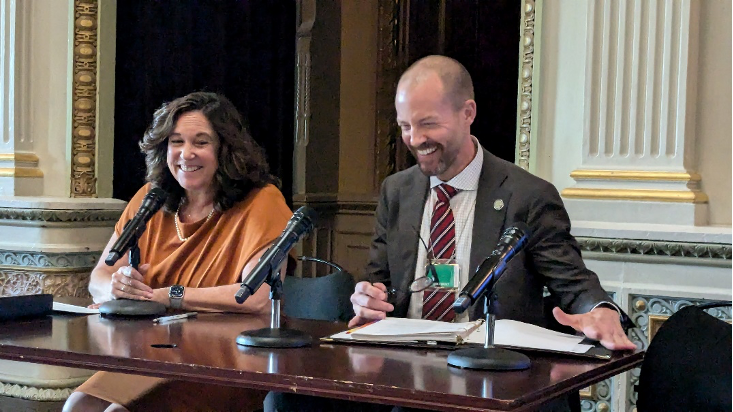 two people speaking in an event in front of microphones